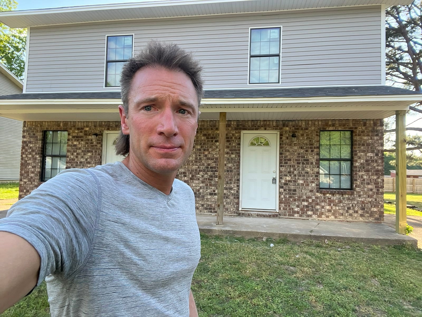 Rusty in front of a brick and siding duplex in Northeast Arkansas